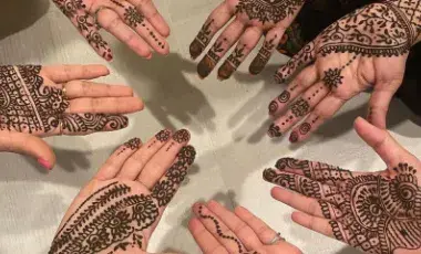 Seven hands featuring henna paste on the palms.