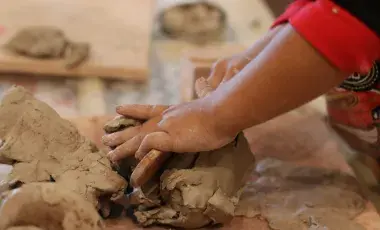 A child's hands explore a mound of clay.