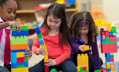 Three girls building towers with blocks. 