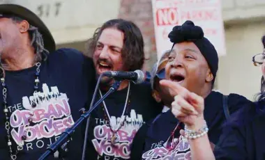 four members from "neighborhood sing" group singing into a microphone