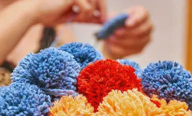 Bunches of homemade pom poms with maker in background