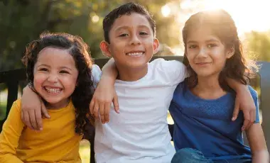 two girls and one boy with arms around each other