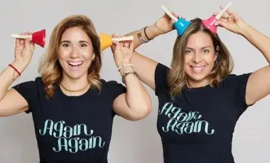 two performers holding up play toys and smiling
