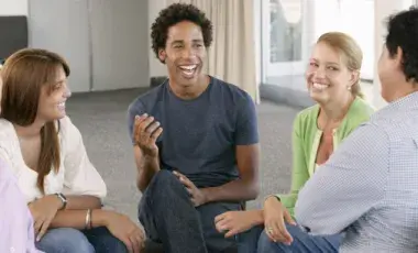 A group of happy adults sitting in chairs in a circle talking