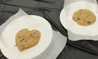 Two Chocolate chip cookies on parchment paper and paper plates