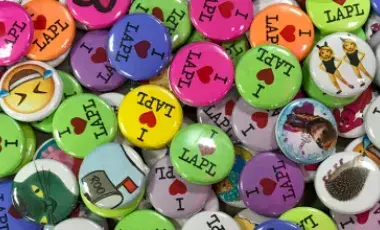 A variety of multicolored 1" buttons with text and images.