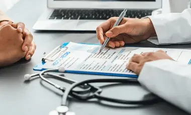  Person in brown sweater sitting and talking to health care professional about their medical record 