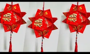 Three red lanterns made of brightly colored red and gold Lunar New Year envelopes are hanging in the image. 