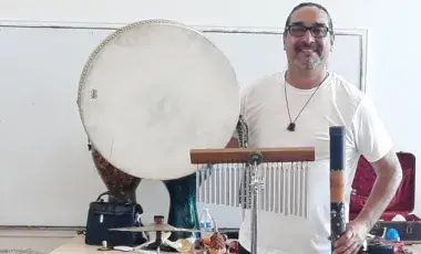 Man with a drum instrument and chimes.
