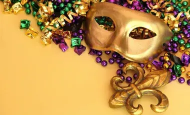 a gold mardi gras masks with gold, green, and purple beads