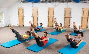 Men and women doing Pilates movements on mats on the floor.