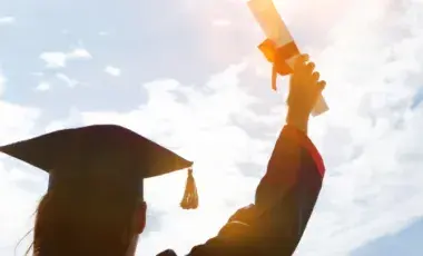Shadow of a person holding up a diploma and wearing a cap and gown