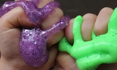 two hands squishing purple and green-lime slime.