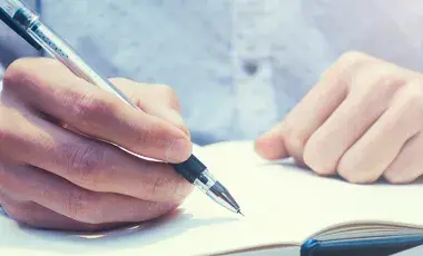 hands writing in notebook