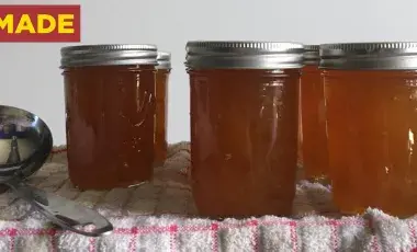4 glass jars filled with jam and a ladle