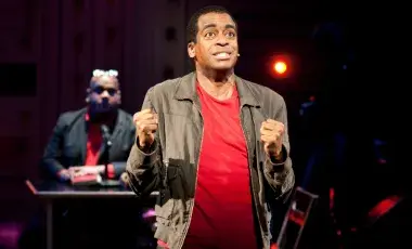 Stew, a young black man is spotlighted on stage 