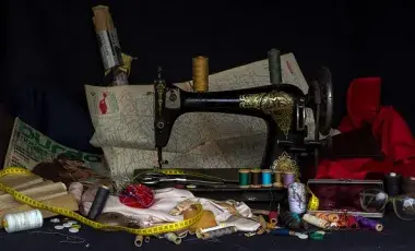 A color photo of a vintage sewing machine, surrounded by sewing paraphernalia, Image by andreas N from Pixabay