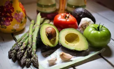 A color photo of asparagus, avocado, garlic, red tomato and green tomato. Image by Jill Wellington from Pixabay