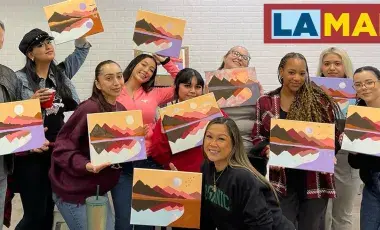 adults smiling while holding up their paintings