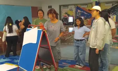 Group of teens stand in a circle around an easel to plan a program. 