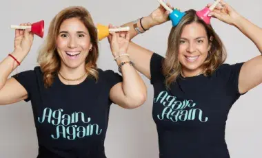 Two musicians playfully hold up musical instruments to their ears