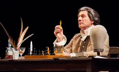Actor dressed as Thomas Paine holding a chess piece.
