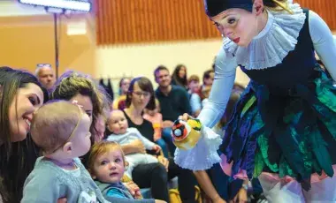 An adult female showing a toy to a baby.