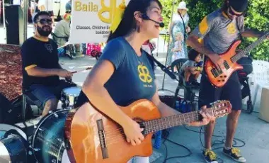 Woman with guitar joyfully singing with band