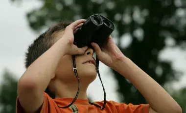 kid lifts binoculars to eyes