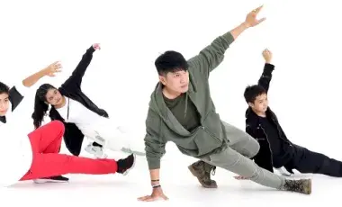 Four people crouching down in a breakdancing pose.
