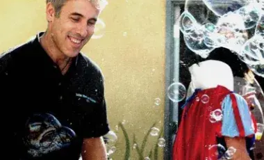 A man smiles surrounded by bubbles