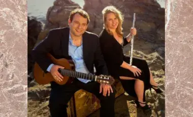 Flutist and guitarist sitting in front of a rocky landscape.