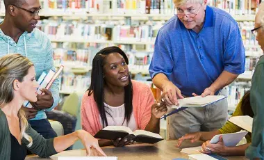 Adults discussing books in library