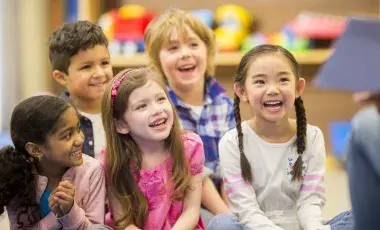 Children smiling at adult reading to them