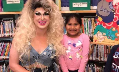 Drag Queen performer "Pickle" poses for a photo with a young patron at the library.