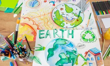 Wooden table with art supplies and drawings of planet earth.