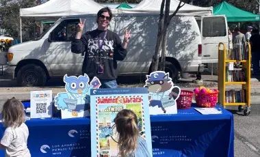 A librarian stands at a table at the Farmer's Market