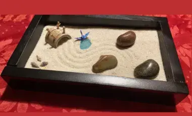Black lacquered box with sand and rocks with rake marks with a red background 