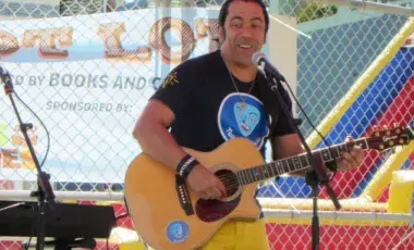 A man plays a guitar while singing into a microphone. 
