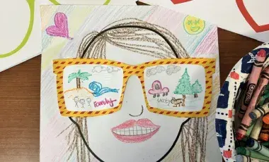 A colorful self-portrait with summer memories drawn onto the lenses of yellow with red striped glasses.