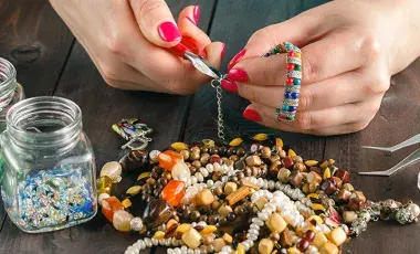 A pair of hands is using a tool to make a bracelet