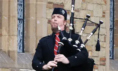 John McLean Allan playing his bagpipe in front of a church