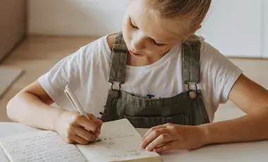 Young girl writing in a journal.