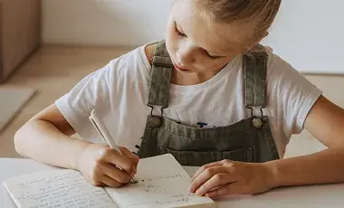 A young girl writing in a journal.