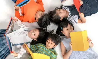 Kids reading books lying in a circle on the ground