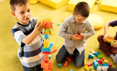 Three boys construct structures using building blocks