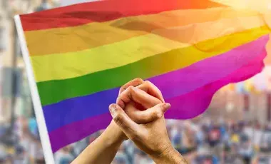lgbtqia flag and hands intertwined