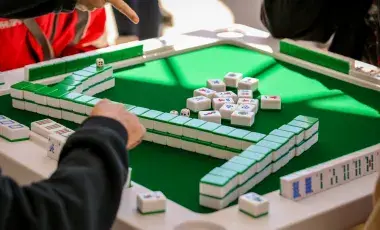 Mah Jongg table with hands playing game. 
