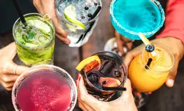 A group of people hold brightly colored drinks together