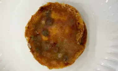 A mini pizza on a paper plate